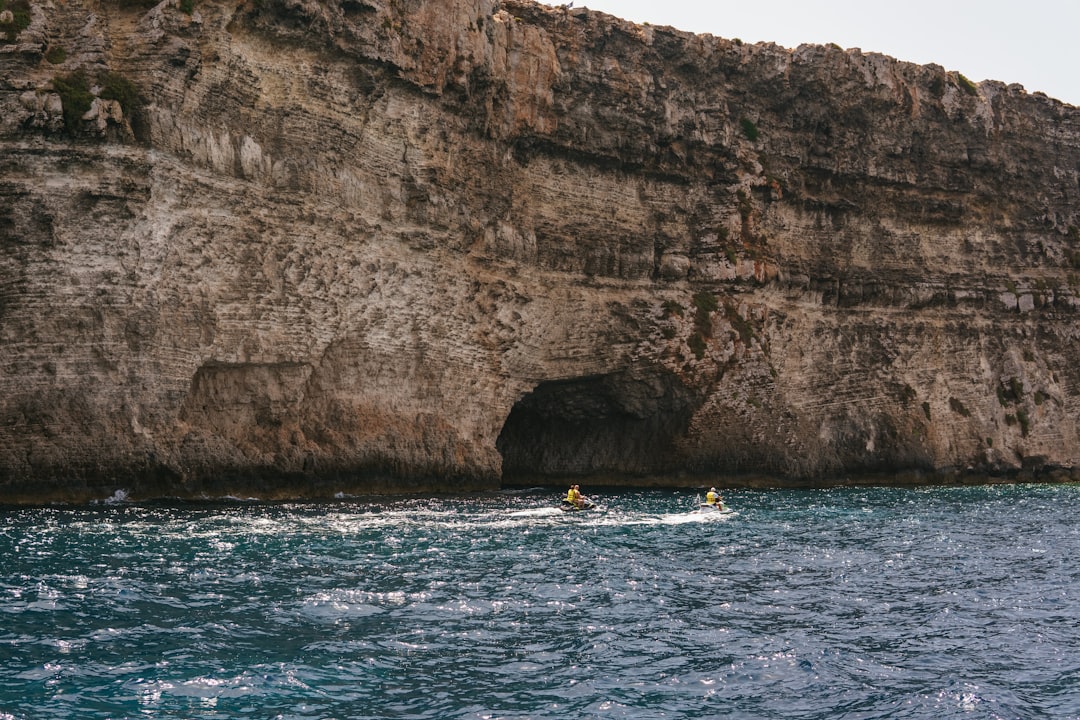 A boat in a body of water near a cliff